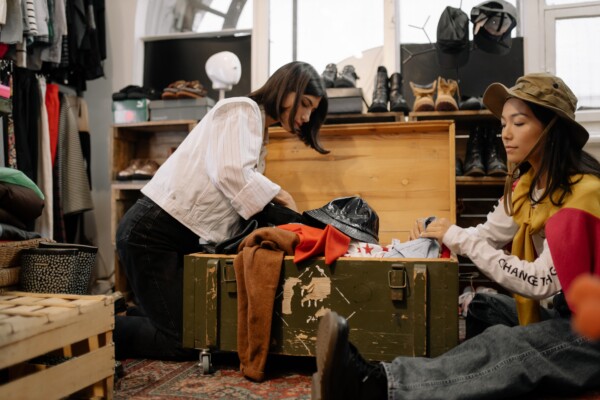2 women look through a chest of used clothes