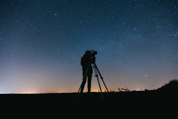 A person looking at the night sky using a telescope