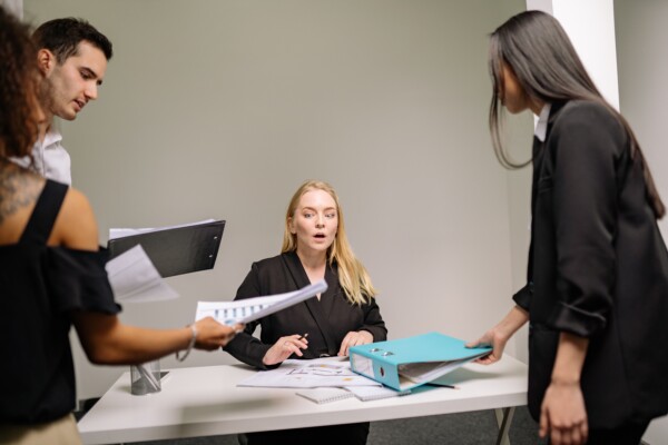 Woman sitting at a desk overwhelmed with paperwork
