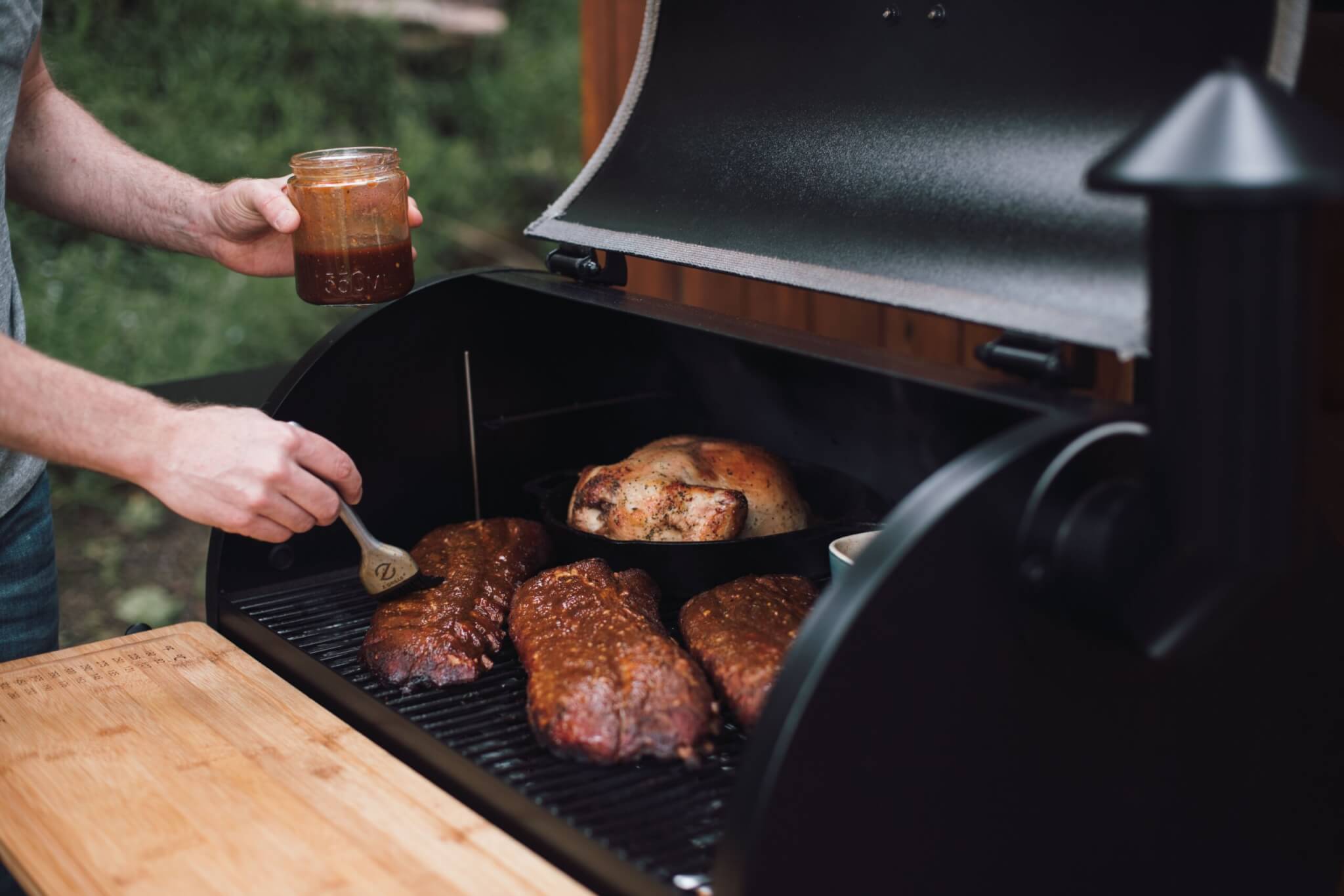 Brushing BBQ sauce on racks of ribs in a Z Grill pellet smoker