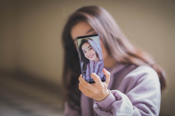 woman in white long sleeve shirt holding black smartphone