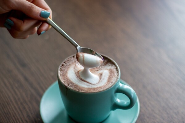 A spoon scoops up foam from a cup of coffee