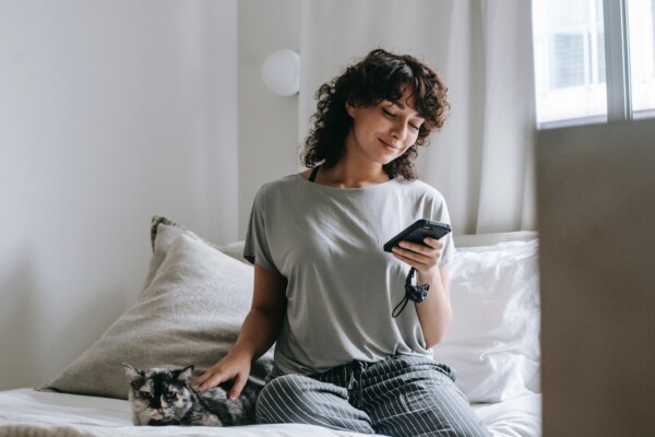 a woman on her phone, petting her cat