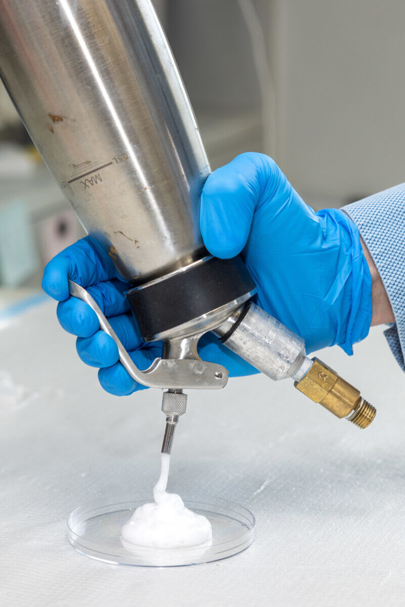 A scientists spraying a white foam that may treat cancer