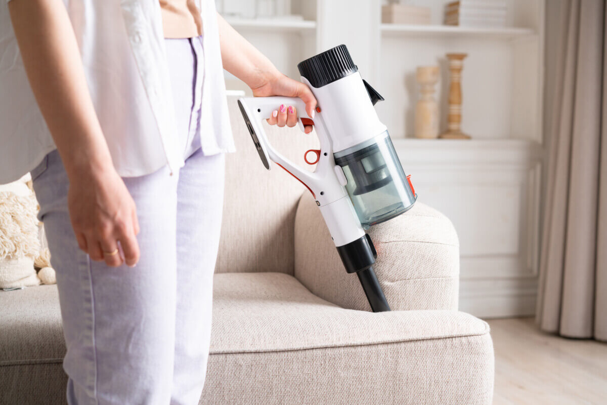 Woman using handheld vacuum on a couch