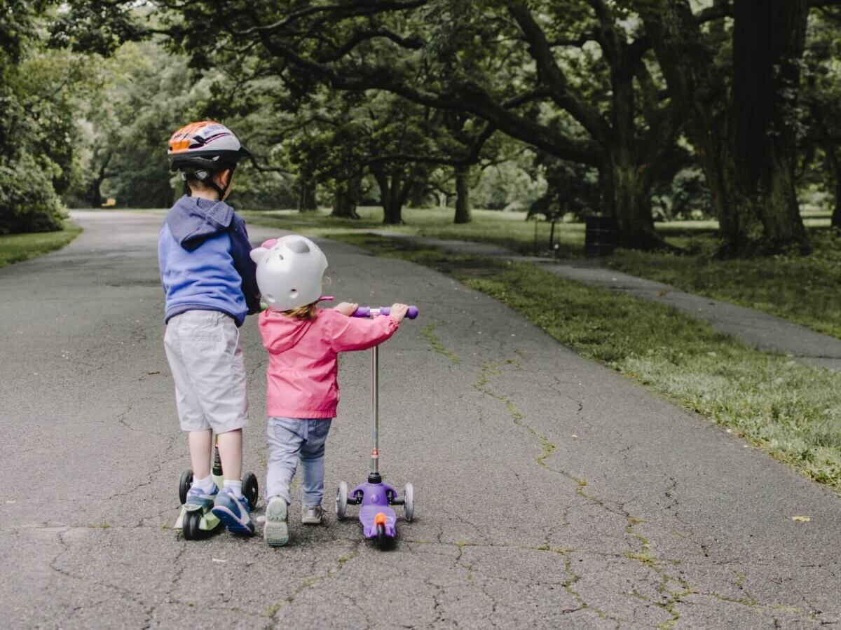 Two children riding a scooter outdoors