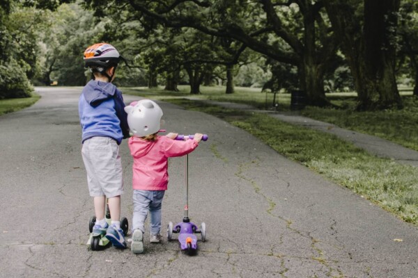 Two children riding a scooter outdoors
