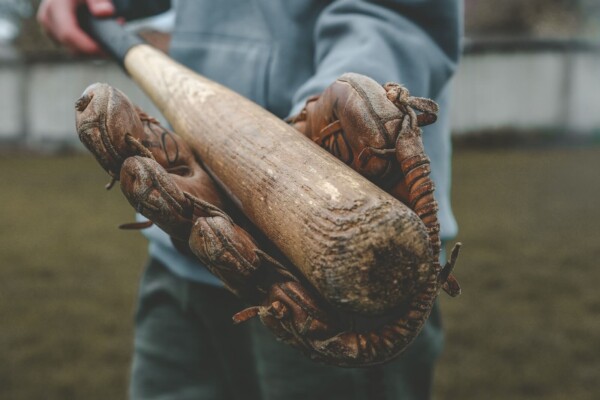 A person holding a baseball bat in a baseball glove