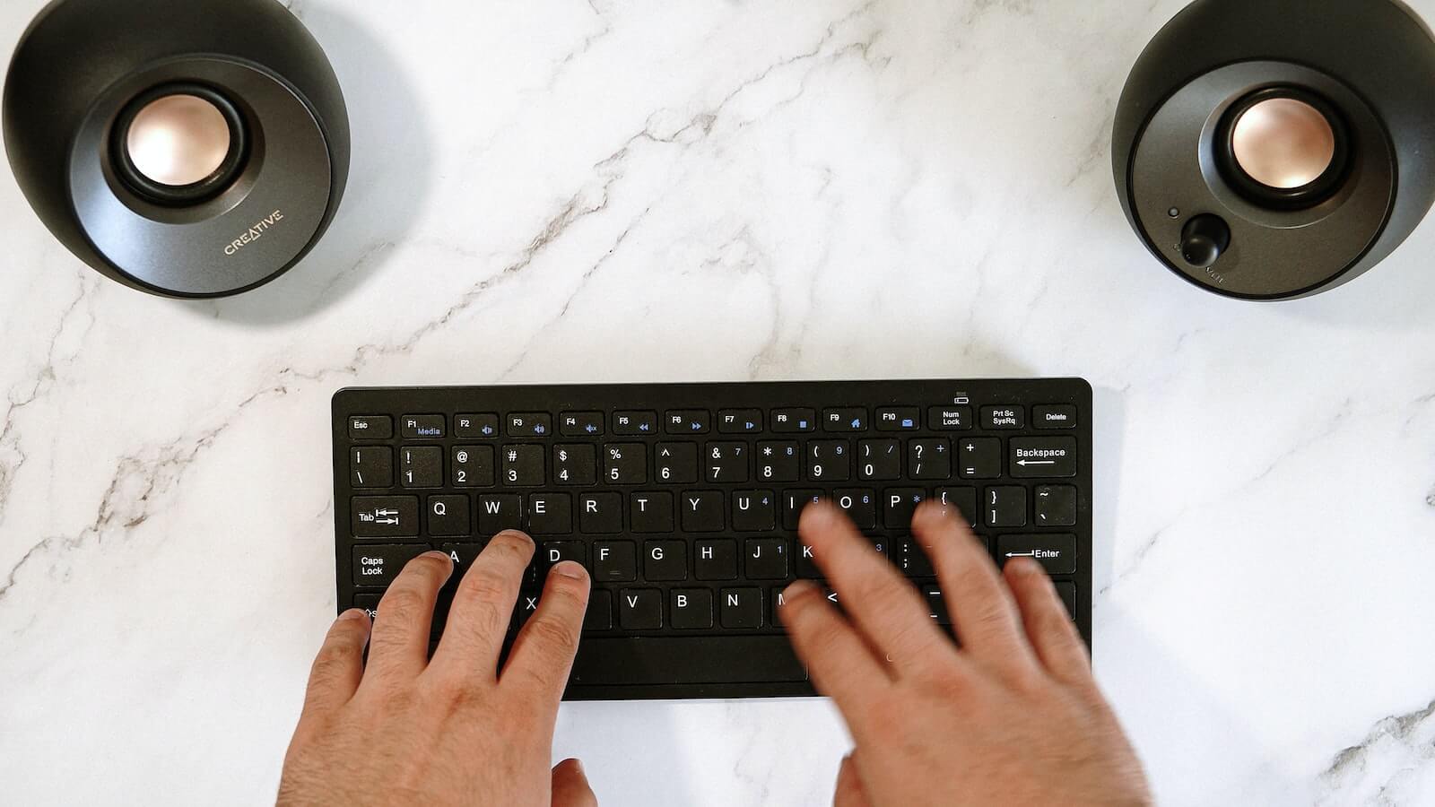 Person typing on a black wireless keyboard