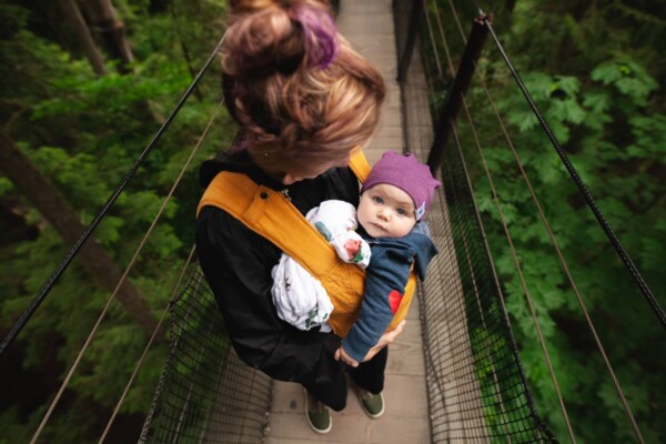 Woman carrying baby on a bridge in the forest