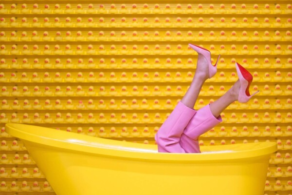 A woman wearing Louboutin's in a yellow bath tub