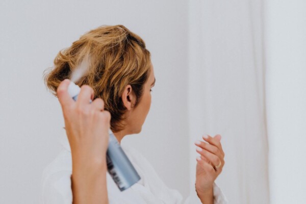 Woman applying dry shampoo to her hair