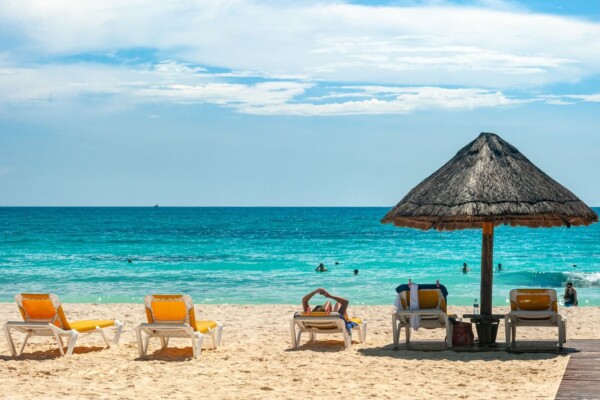 Beach chairs and umbrella in front of turquoise water on the beach in Mexico