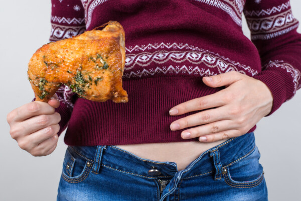 A woman holding her full stomach and a turkey leg