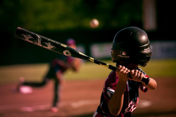 A kid swinging a metal bat during a baseball game