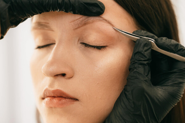 Person plucking a woman's eyebrow