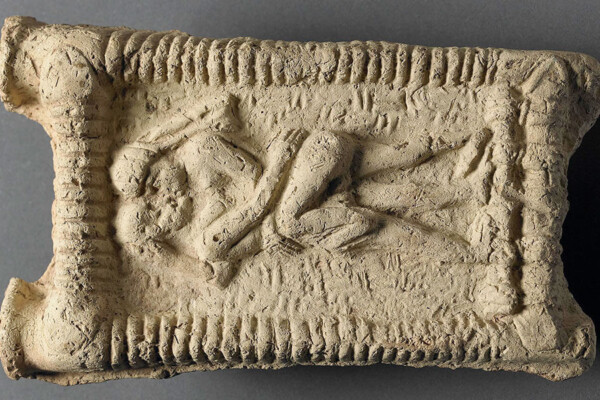 Babylonian clay model showing a nude couple on a couch engaged in sex and kissing.