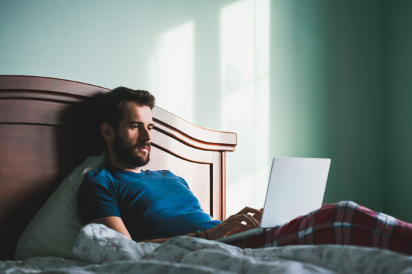 Man working on laptop computer in bed