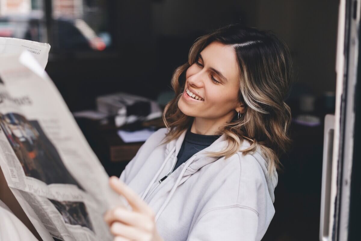 Woman smiles while reading newspaper