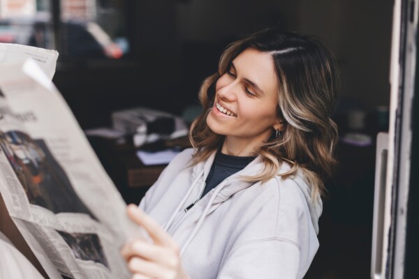 Woman smiles while reading newspaper