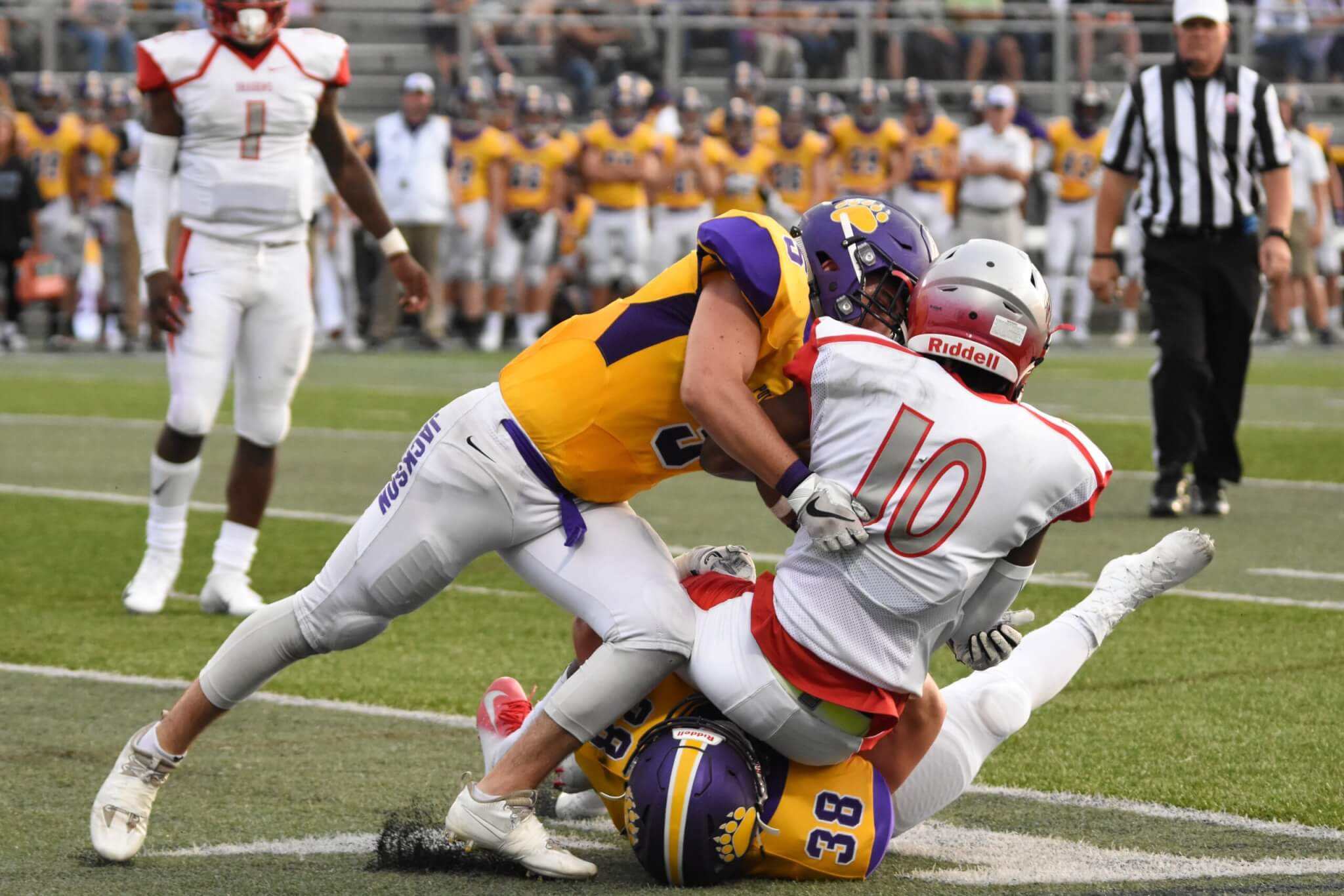 Football players tackling each other on grass field.