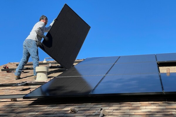 Man installing solar panel on house