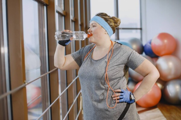 Woman Drinking Water in Gym