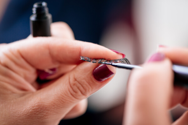 Someone applying glue to the base of false eyelashe