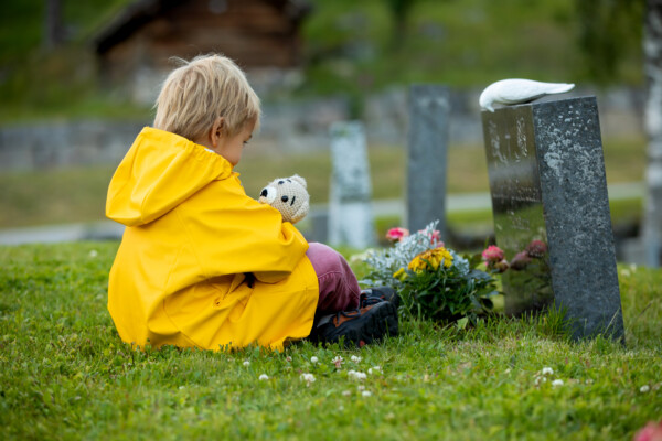 Sad boy mourning in cemetery