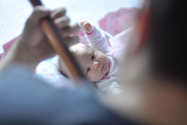 Baby lying on bed while adult plays music