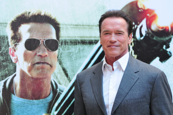 Arnold Schwarzenegger standing in front of a poster for "The Last Stand" in 2013