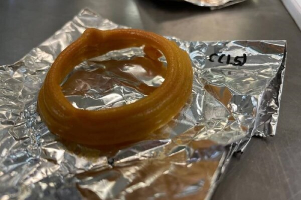 3d printed brown edible calamari ring sits on top of a sheet of foil.