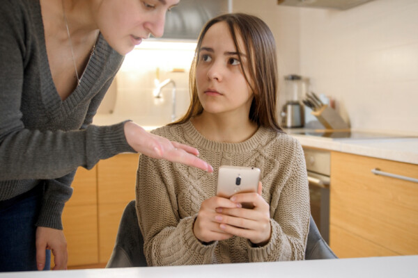 Mother taking away smartphone from teen daughter.