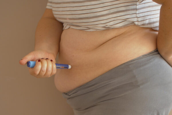 Overweight woman applying medicine injection