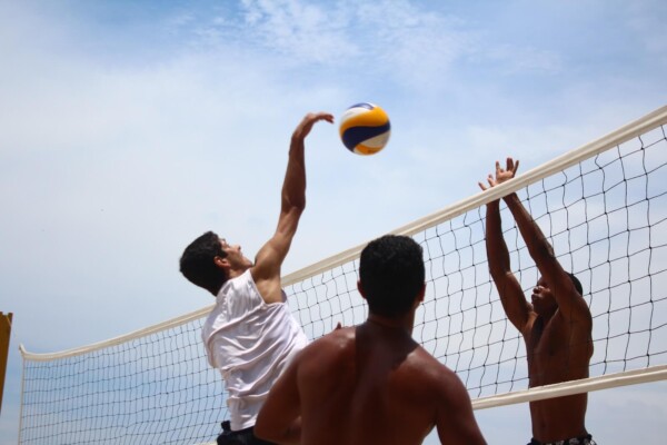 A man spiking a volleyball over a net