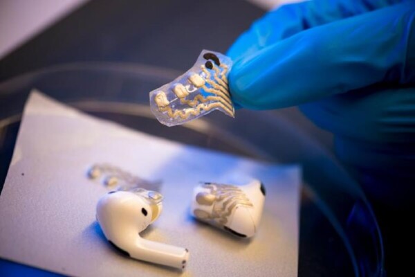 a pair of white bluetooth earbuds with screen-printed sensors attached to them