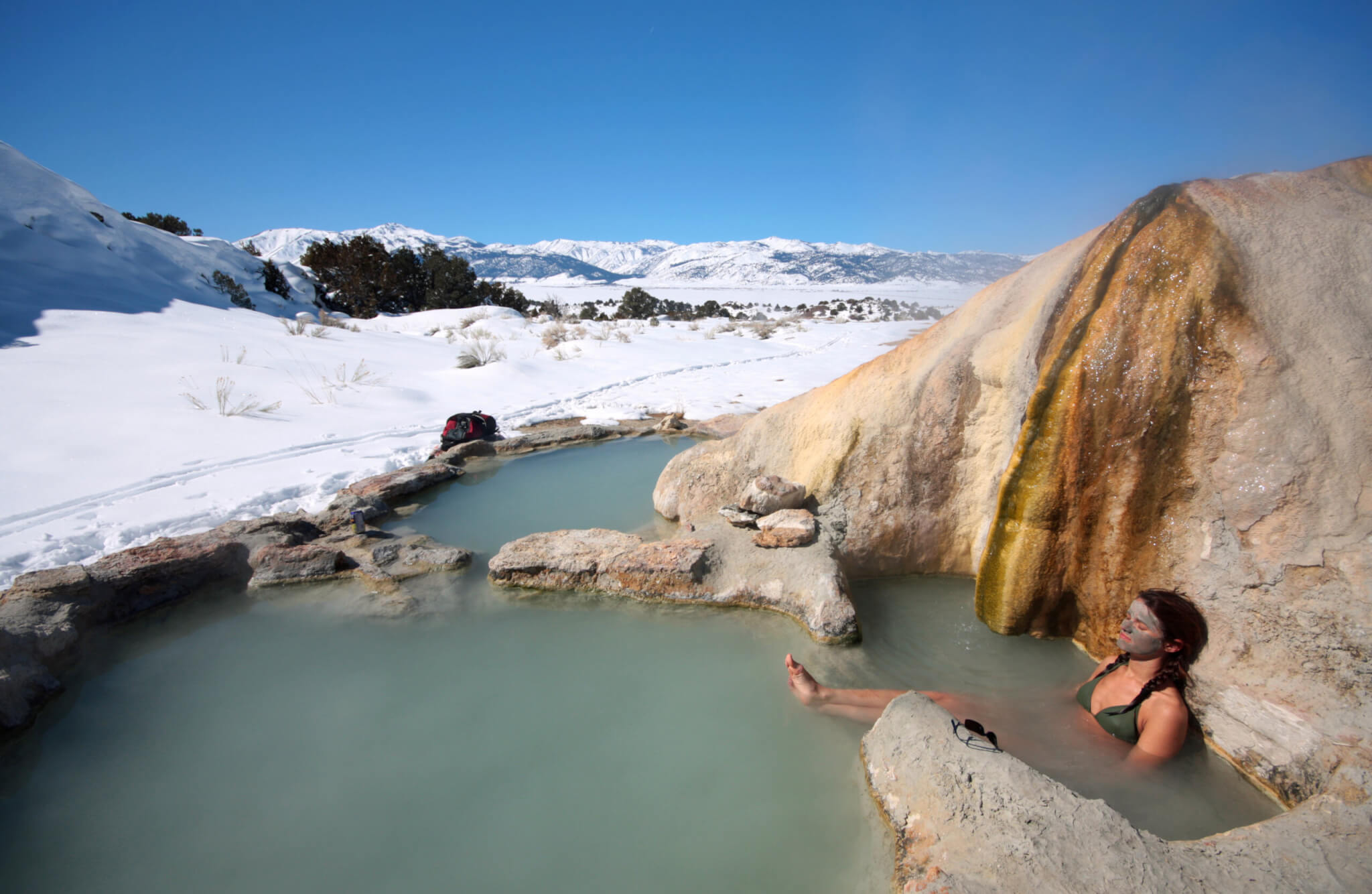A woman soaking with a mud mask in the Travertine Hot Springs