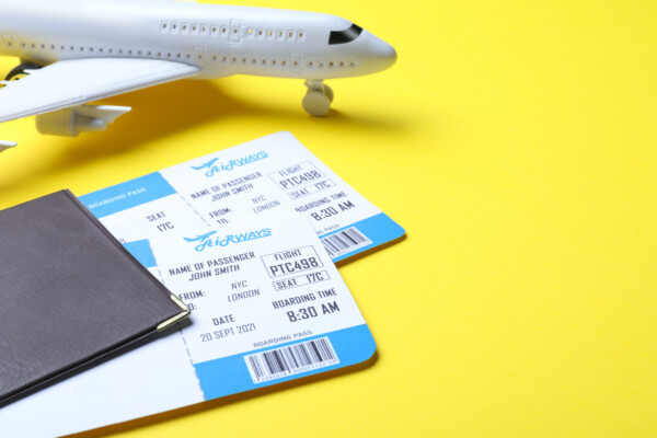 Passport with tickets and toy airplane on yellow background.