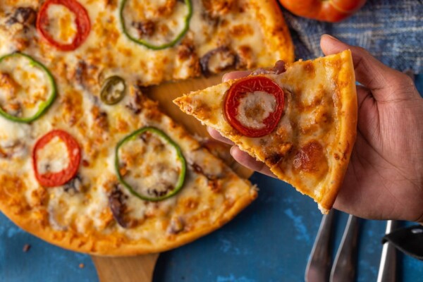 Sliced pizza on brown wooden round plate