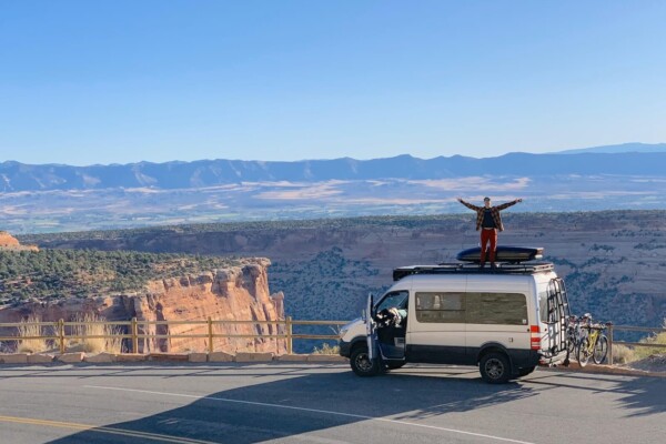 A man standing on top of a converted sprinter van