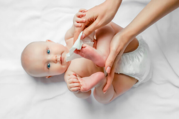 A mother wiping off her baby with a wipe