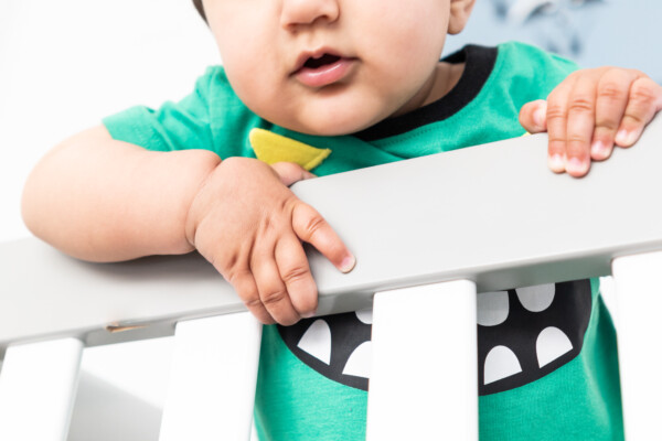 A baby behind a bed rail
