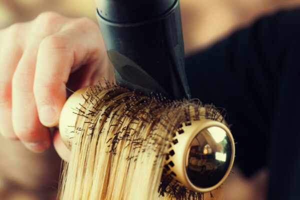 Someone drying their hair with a round brush