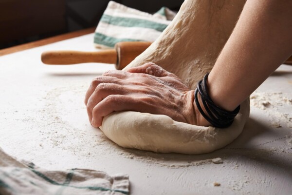 Someone kneading pizza dough