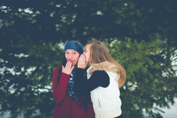 woman whispering in woman's ear