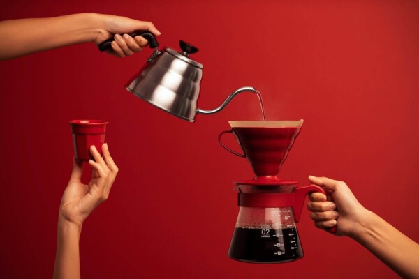Someone pouring hot water from a kettle into a coffee pot