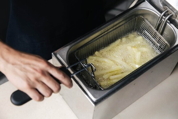 Someone frying French fries in a deep fryer
