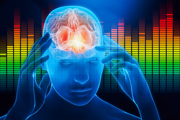 Person with hands touching temples with sound levels in the background.