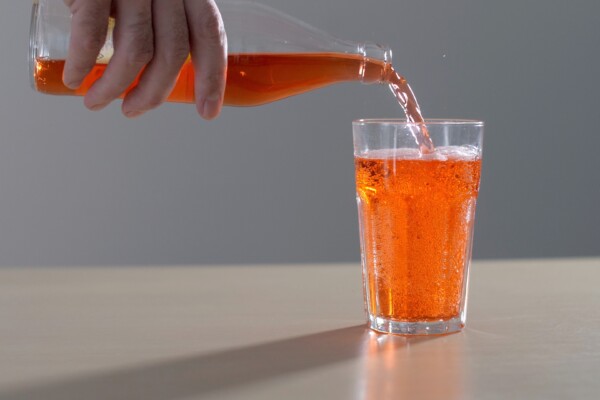 Pouring glass of orange soda