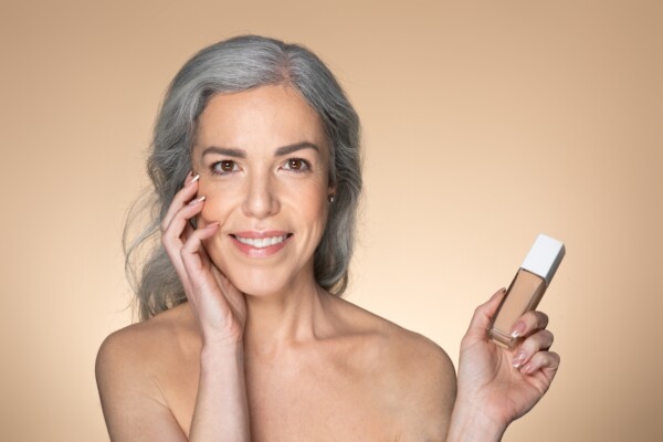 An older woman with a bottle of foundation